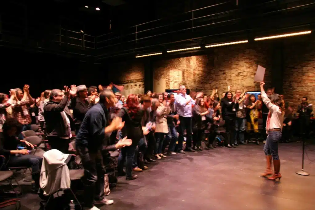 2013 Latinx Theatre Commons National Convening in Boston, Massachusetts - a person speaking in front of a standing and applauding audience