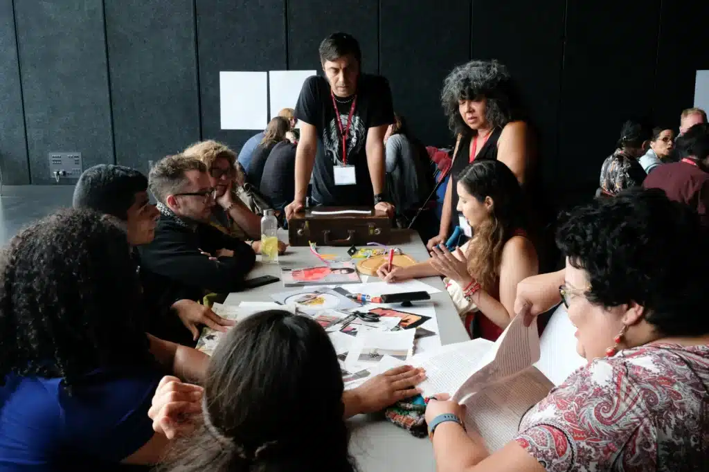 Nine people at a table sorting through magazines and writing things on paper.